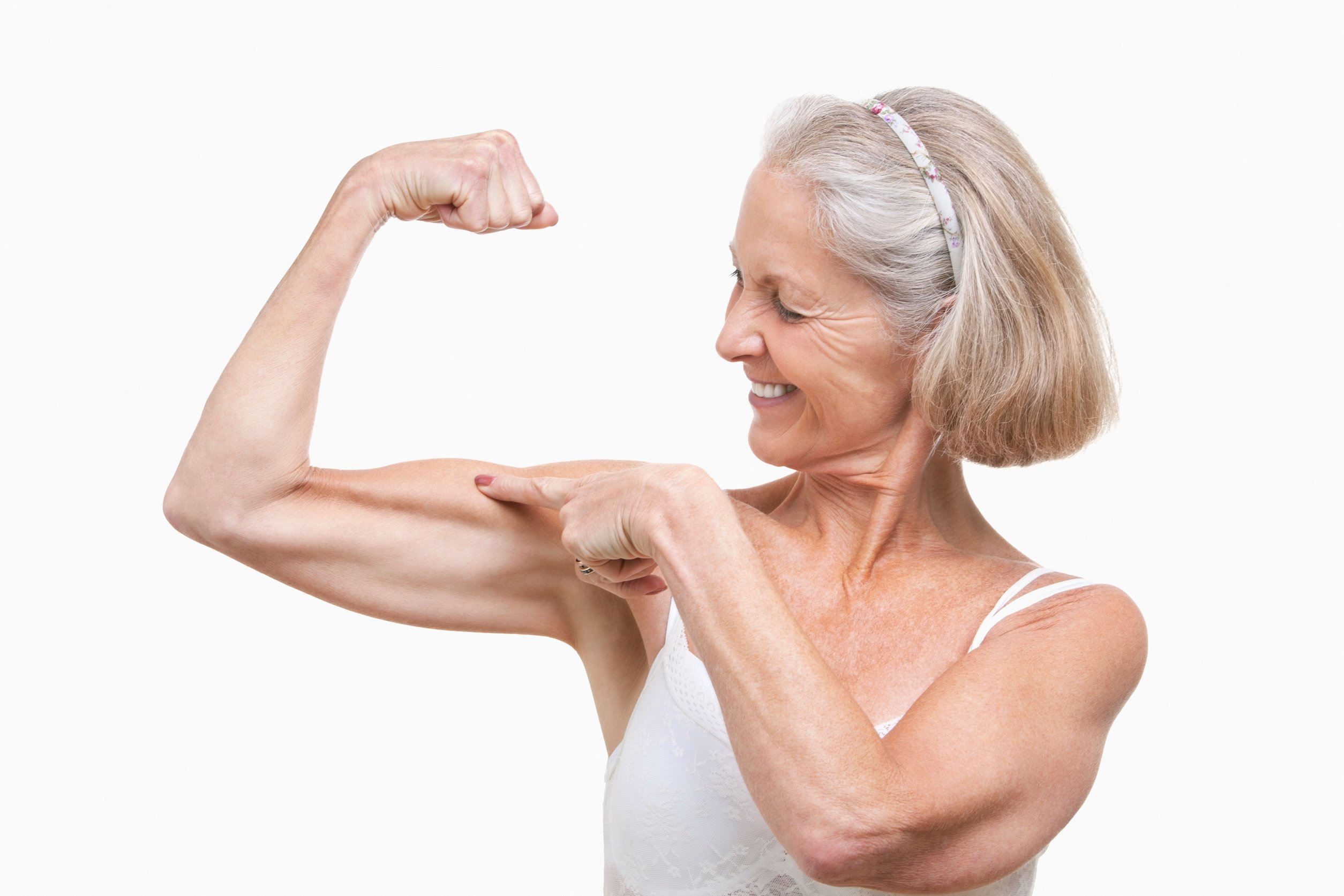 Senior woman flexing muscles against white background