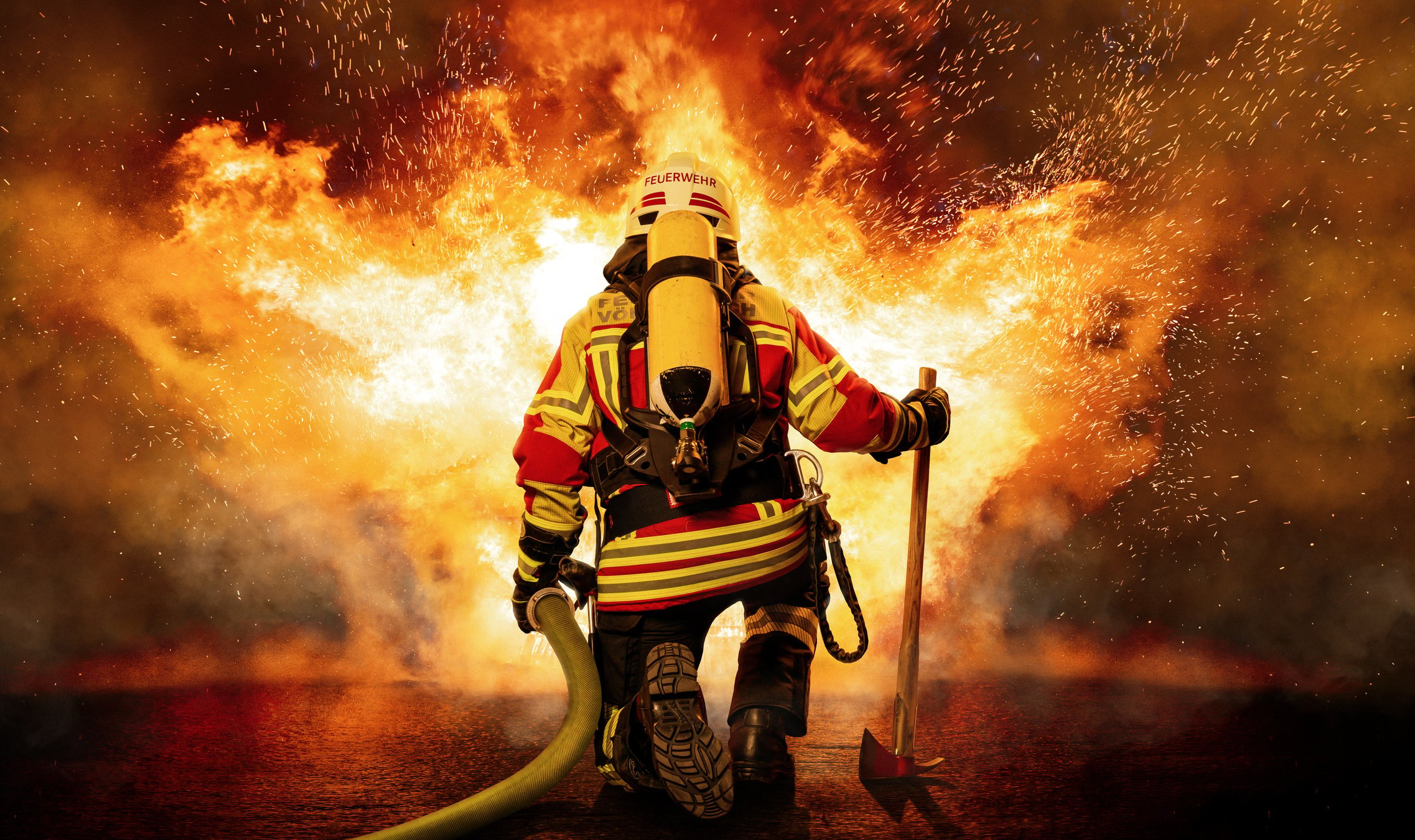 A firefighter kneels before the fire